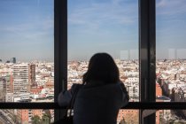 Anonyme Frau schaut aus Balkonfenster — Stockfoto