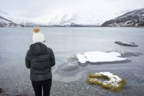 Анонімна людина на березі ставка проти високогір'я взимку — стокове фото