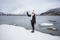 Joven asiático mujer en estanque orilla contra highland en invierno - foto de stock