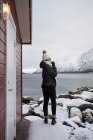 Mujer solitaria en la costa rocosa contra el lago tranquilo y nevado mo - foto de stock