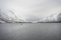 Lago tranquilo contra colinas nevadas em tempo nublado frio — Fotografia de Stock