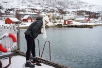 Femme sur le front de mer contre une petite ville au pied des neiges — Photo de stock
