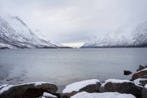 Спокойное озеро против снежных холмов в холодную погоду — стоковое фото