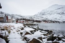 Ruhiger See vor verschneiten Hügeln bei kaltem, bewölktem Wetter — Stockfoto