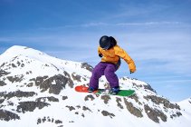 Невідомий сноубордист стрибає на схилі — стокове фото