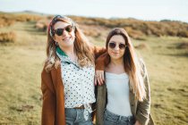 Stylish cheerful women standing on green field — Stock Photo