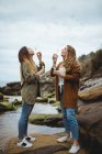 Felice femmina amici soffiando bolle in riva al mare — Foto stock