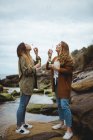 Happy female friends blowing bubbles on seashore — Stock Photo