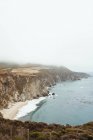 Блакитні хвилі миття скелястого узбережжя в яскравий день — стокове фото