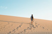 Homme seul avec sac à dos marchant dans le désert de sable — Photo de stock