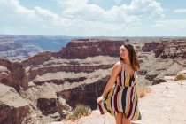 Mujer alegre en vestido de rayas ligeras girando en las montañas - foto de stock