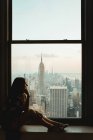 Femme poignante regardant par la fenêtre — Photo de stock