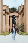 Aktive Frau spaziert zwischen alten Säulen des Gebäudes im Freien — Stockfoto