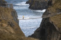 Турист, идущий по веревочному мосту между скалами Севера — стоковое фото