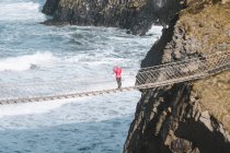 Turista caminando en puente de cuerda suspendido entre acantilados en el norte - foto de stock