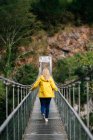 Allegro turista donna in piedi sul ponte sospeso in estate — Foto stock