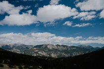 Діапазон широкого гірського хребта з лісами під блакитним небом з кумульськими хмарами вдень — стокове фото
