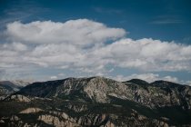 Gamme de vastes chaînes de montagnes avec des forêts sous le ciel bleu avec des cumulus en journée — Photo de stock