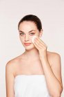 Peaceful woman applying toner on radiant face with sponge — Stock Photo