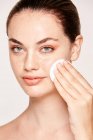 Mulher sardenta limpeza rosto rosto pele com loção em esponja de algodão isolado no fundo branco — Fotografia de Stock