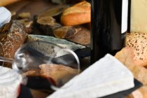 Saboreie fatias caseiras de queijo branco e pão crocante fresco com garrafa e copo de vinho tinto na mesa de madeira rústica — Fotografia de Stock