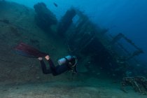 Scuba divers swimming underwater exploring wreckage — Stock Photo