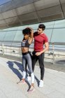 Un homme athlétique aide une Afro-Américaine active à faire un exercice d 