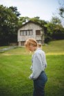 Vue latérale d'une jeune femme calme et décontractée profitant d'une promenade dans un pré verdoyant près d'une maison en bois dans un village rural des Asturies, Espagne — Photo de stock