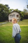 Side view of casual calm young woman enjoying stroll on green meadow near wooden house in rural village in Asturias, Spain — Stock Photo