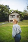 Vue latérale d'une jeune femme calme et décontractée profitant d'une promenade dans un pré verdoyant près d'une maison en bois dans un village rural des Asturies, Espagne — Photo de stock
