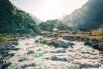 Powerful mountain river streaming through stones in bright sunny daytime in Switzerland — Stock Photo