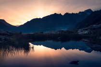 Breathtaking landscape of motionless water reflecting sky in warm sunset light and mountains in Switzerland — Stock Photo