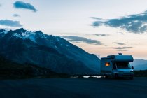 Кампер - ван, що їде по дорозі вздовж озера з кришталевою водою в сутінках у Швейцарії. — стокове фото