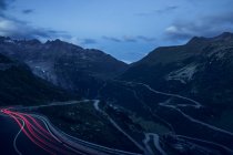 Evening landscape of serpent road with red lights of cars in long exposure curving in mountains in Switzerland — Stock Photo