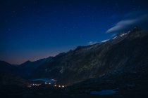 Горный хребет и река между склонами с огнями выше в Швейцарии — стоковое фото