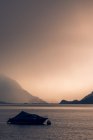 Calm landscape of dark boat in wavy water under gray cloudy sky in mountains in Switzerland — Stock Photo
