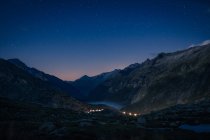 Mountain range and river between slopes with lights above in Switzerland — Stock Photo