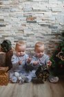 Bebés examinando regalos de Navidad en casa - foto de stock