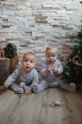 Bebés examinando regalos de Navidad en casa - foto de stock