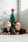 Gêmeos no chão perto da árvore de Natal — Fotografia de Stock