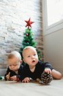 Jumeaux sur le sol près de l'arbre de Noël — Photo de stock
