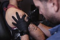 Майстер робить татуювання на передпліччі чоловічого клієнта — стокове фото