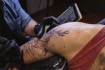 Мастер делает татуировку на предплечье клиента-мужчины — стоковое фото