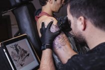 Мастер делает татуировку на предплечье клиента-мужчины — стоковое фото
