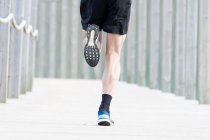 Abgeschnittenes Bild eines männlichen Athleten, der unter Deckung im Freien rennt — Stockfoto