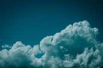 Aerial view from airplane window of white fluffy clouds and beautiful dark turquoise sky — Stock Photo