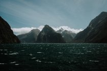 Majestosas montanhas escuras e pacífico lago sob o céu azul na Nova Zelândia — Fotografia de Stock