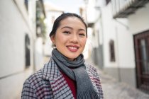 Радісна жінка-туристка в повсякденному одязі посміхається в камеру серед міської вулиці — стокове фото
