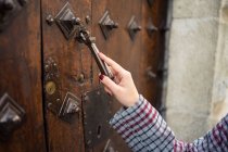 La main de la voyageuse en tenue décontractée claquent dans la porte antique de la rue de la ville — Photo de stock