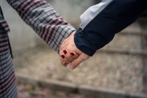 Close-up de casal casual segurando as mãos e passeando na cidade — Fotografia de Stock